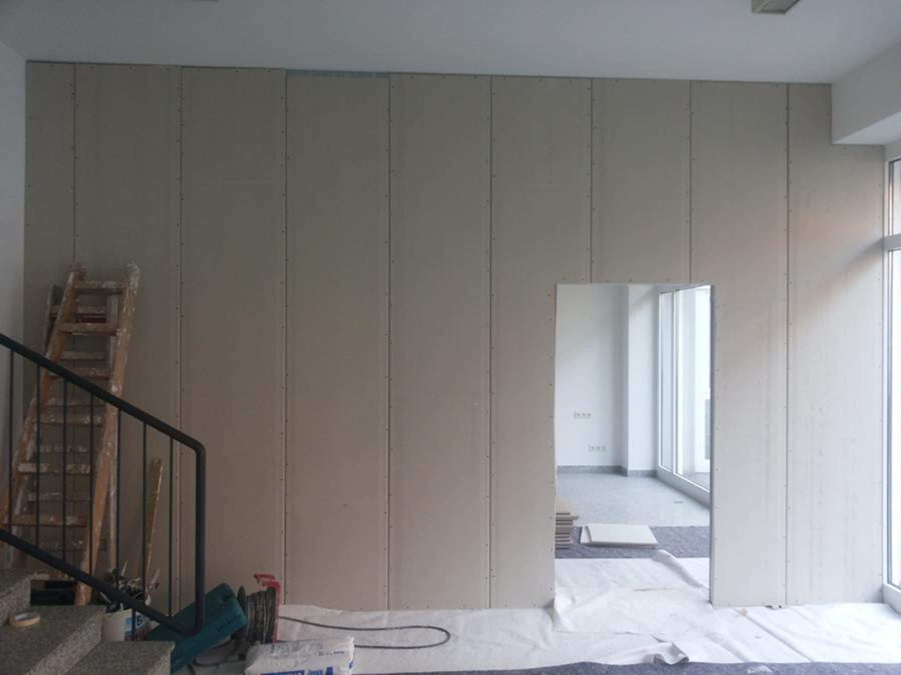 Farbrolle zieht kräftiges Blau über eine weiße Wand
